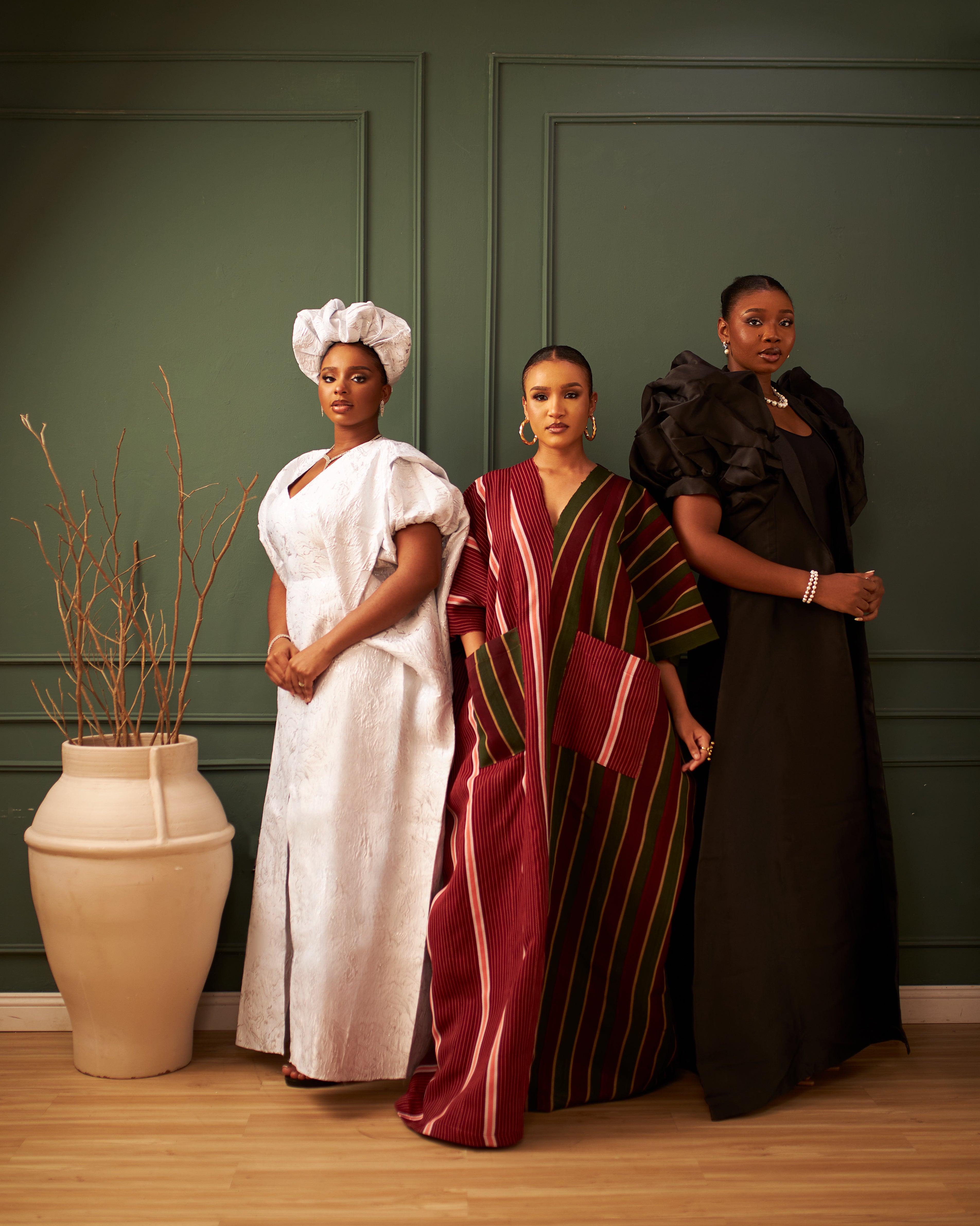 Three women in a white kaftan, a burgundy striped kaftan, and a black dress.