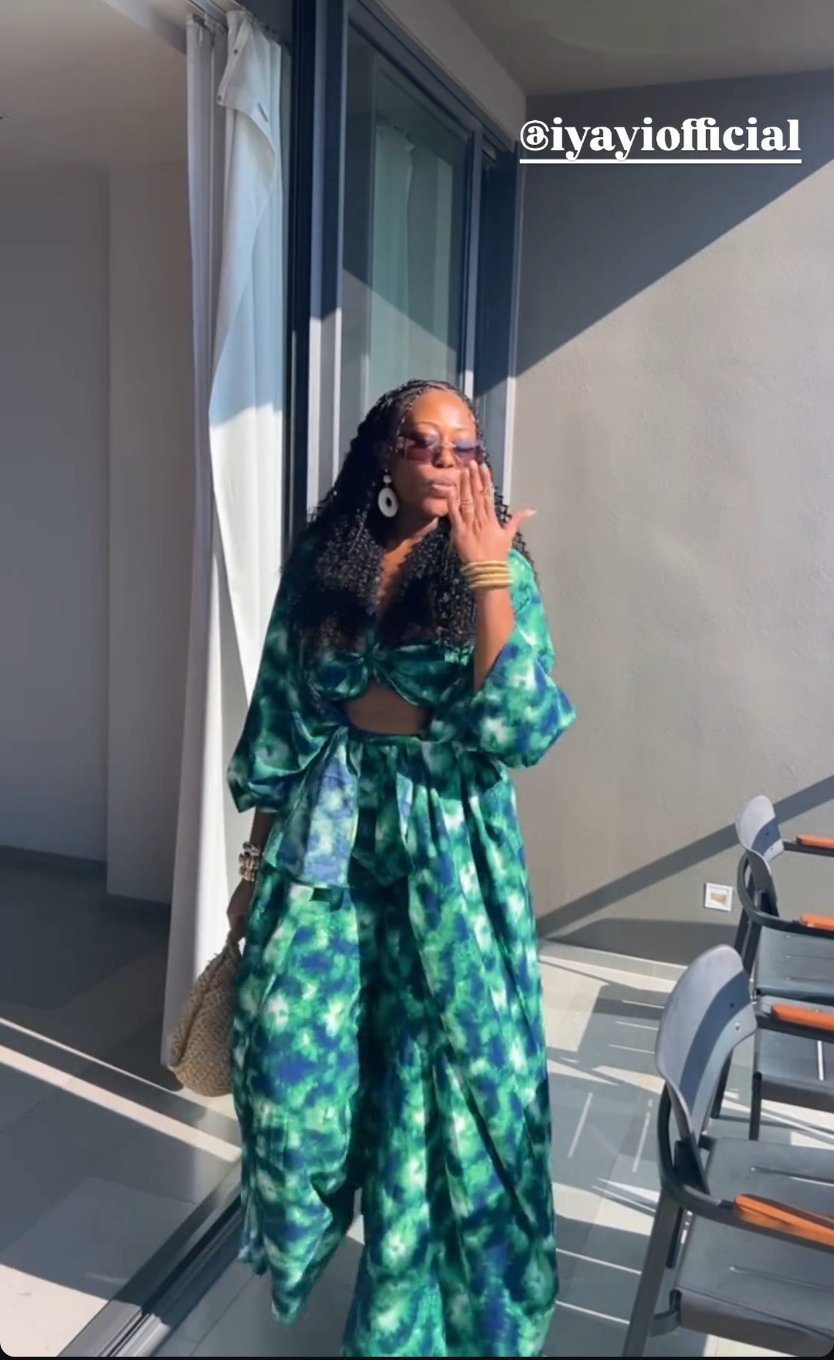 Woman wearing the green printed Sama four-piece pant set on a balcony.